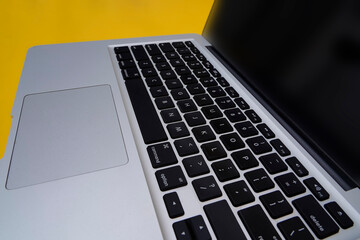 Modern aluminum computer or laptop keyboard isolated yellow background
