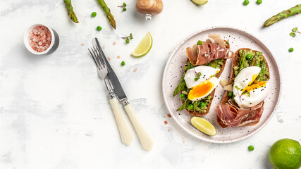 Grilled Toast witch Asparagus, Poached egg, bacon jamon, ham, prosciutto on white background. banner, menu recipe place for text, top view