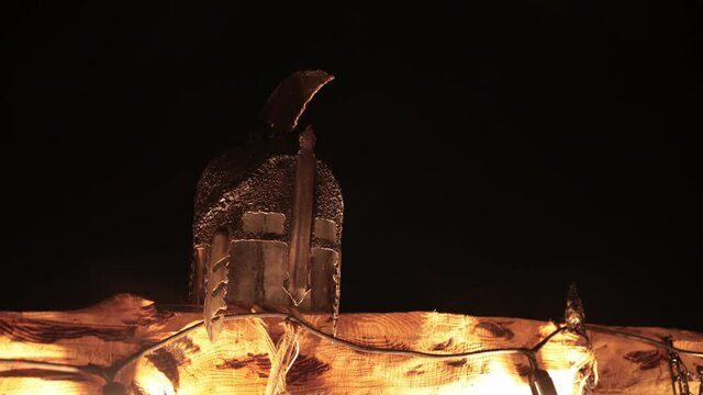 Battle helmet for a brave fight against the enemy defending the viking. Pedestal for fighting between opponents, ritual place of ancient vikings with torches, ring. Night, low light.