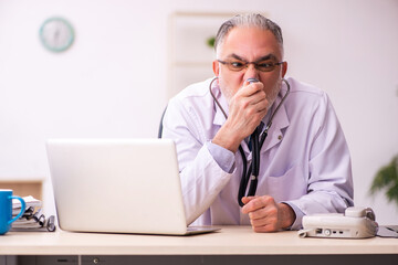 Aged male doctor working in the clinic