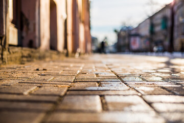 Streets in the late autumn, sidewalk illuminated sun. Close up view from the sidewalk level