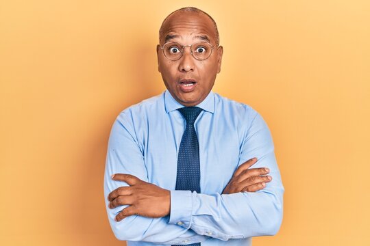 Middle age latin man wearing business clothes with arms crossed gesture afraid and shocked with surprise and amazed expression, fear and excited face.