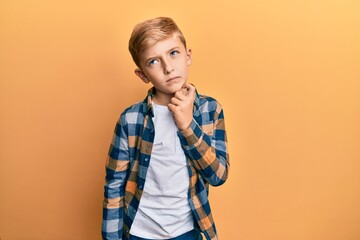 Little caucasian boy kid wearing casual clothes serious face thinking about question with hand on...