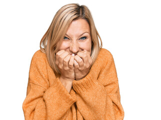 Middle age caucasian woman wearing casual winter sweater laughing and embarrassed giggle covering...
