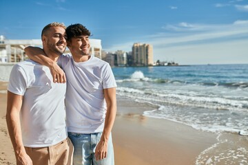 Young gay couple smiling happy walking at the beach.