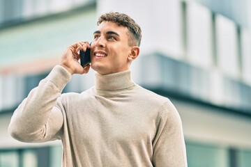 Young hispanic man smiling happy talking on the smartphone at the city.