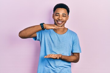 Young african american man wearing casual blue t shirt gesturing with hands showing big and large size sign, measure symbol. smiling looking at the camera. measuring concept.