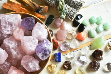 A top view image of a bowl of rose quartz crystals with several other healing crystal and smudge sticks.  - obrazy, fototapety, plakaty
