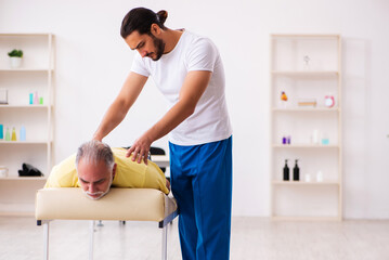 Old male patient visiting young male doctor chiropractor