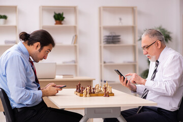 Two businessmen playing chess in the office