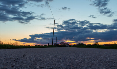 Bottom view road, street leading to small Czech village at sunset with electric wiring