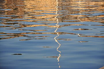 Abstract reflection of colorful Rijeka building on sea. Sea surface with gold effect.