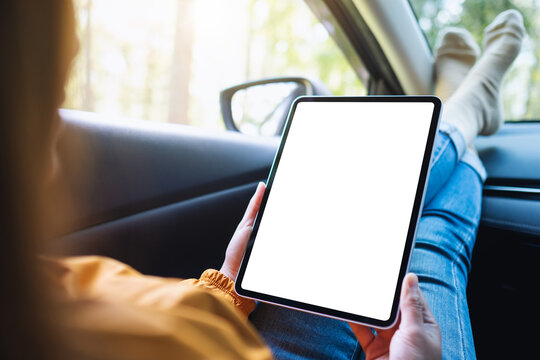 Mockup image of a woman holding and using digital tablet with blank screen while laying in the car