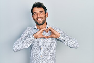 Handsome man with beard wearing casual elegant shirt smiling in love showing heart symbol and shape...