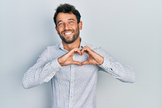 Handsome man with beard wearing casual elegant shirt smiling in love showing heart symbol and shape with hands. romantic concept.