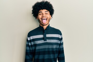 Fototapeta na wymiar Young african american man with afro hair wearing casual clothes sticking tongue out happy with funny expression. emotion concept.