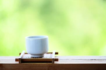 Sake cup on a wooden table Natural green backdrop Celebration idea
