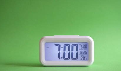 Digital alarm clock on table with green background. Copy space. - obrazy, fototapety, plakaty