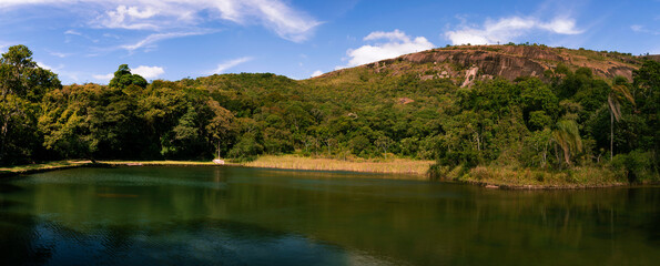 Fototapeta na wymiar Panorama of natural landscape with lake in the mountain of Big Stone. Water mirror with the location's reflection. Atibaia, Brazil.
