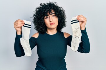 Young middle east woman holding socks relaxed with serious expression on face. simple and natural looking at the camera.