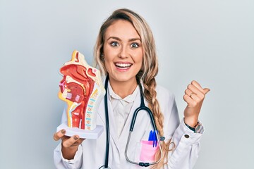 Beautiful young blonde woman holding anatomical model of respiratory system pointing thumb up to...