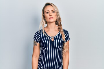 Obraz premium Beautiful young blonde woman wearing casual striped dress relaxed with serious expression on face. simple and natural looking at the camera.