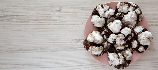 Homemade Chocolate Crinkle Cookies on a pink plate, top view. Flat lay, overhead, from above. Copy space.