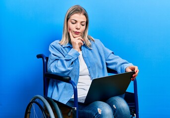 Beautiful caucasian woman sitting on wheelchair using laptop serious face thinking about question...