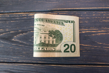 A bill of 20 dollars on a wooden background.