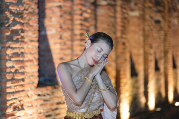 Woman in Thai traditional dress costume, Asian woman wearing Thai dress walking around Ancient City at night.