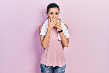 Young brunette woman wearing sportswear and towel shocked covering mouth with hands for mistake. secret concept.