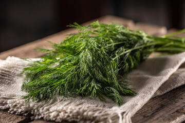 Fresh dill on a linen cloth and wooden surface