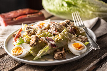 Caesar salad with boiled eggs, bacon, and croutons served on a plate
