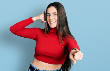 Young brunette teenager wearing red turtleneck sweater smiling doing talking on the telephone...