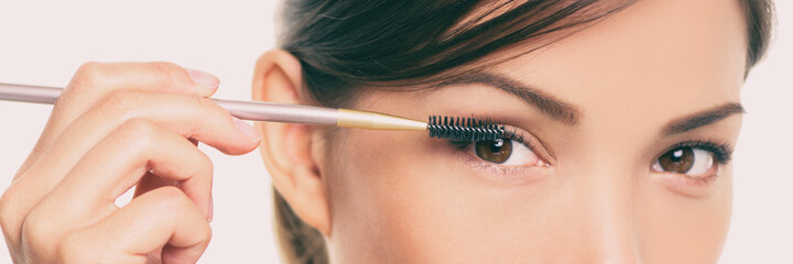Beauty eyes lash lift. Eye makeup Asian woman applying mascara on eyelashes with make-up brush...