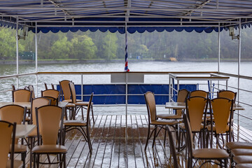 Empty chairs on wet deck of tourist ship on cloudy rainy day