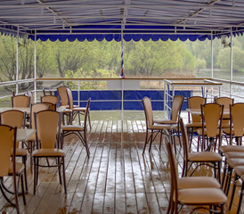 Empty chairs on wet deck of tourist ship on cloudy rainy day