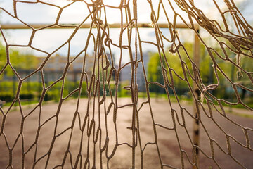 torn soccer net close-up on the background of a soccer field