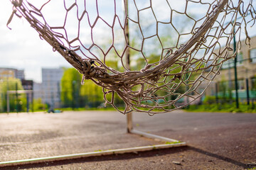 torn soccer net close-up on the background of a soccer field