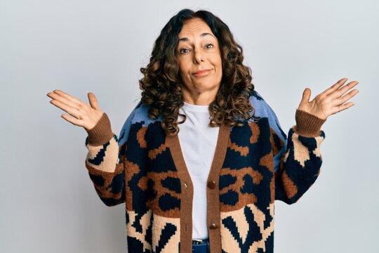 Middle age hispanic woman wearing casual clothes clueless and confused with open arms, no idea and doubtful face.