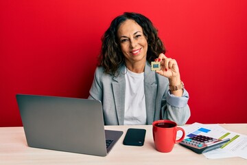 Beautiful middle age woman holding cpu computer processor looking positive and happy standing and smiling with a confident smile showing teeth