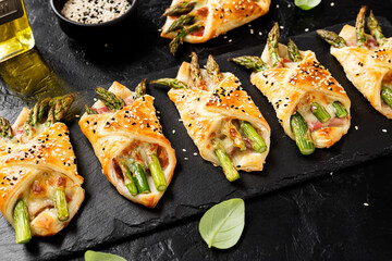 Baked green asparagus with ham and cheese in puff pastry sprinkled with sesame seeds and green...