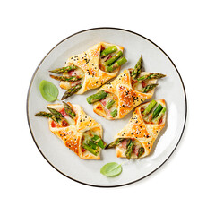 Baked green asparagus with ham and cheese in puff pastry sprinkled with sesame seeds and green basil leaves. isolated on white background, top view