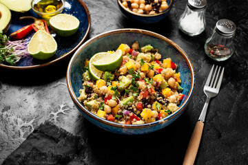 Healthy quinoa black bean salad with mango and avocado. Perfect for spring, summer, fall or winter. Black stone background.