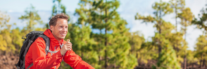 Eating granola bar snack on forest hike happy camper man hiking in nature landscape holding healthy...