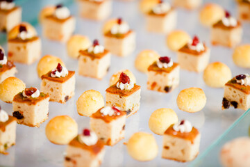 Exquisite creamy berry grape cake and coconut milk shortbread balls are arranged on the dessert table of a Western-style outdoor wedding