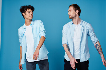 two friends in an unbuttoned shirt and in white t-shirts on a blue background gesturing with hands cropped view party 