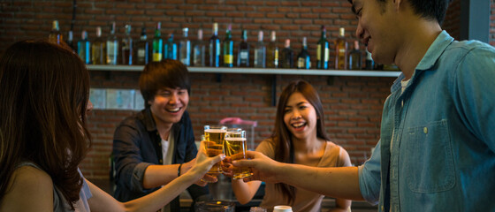 Banner photo of group of Asian friend clinking a glass of beer and enjoy drinking beer at bar, alcohol, beer drinking, friend party, casual meeting, bar and restaurant or friend and beer concept