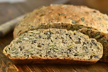 Homemade whole grain bread with seeds on a wooden background