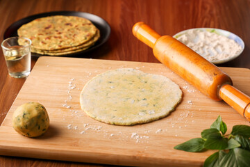 Wooden roller wheat dough  making Palak paratha spinach paratha , parantha , chapati Indian flatbread roti made from spinach with yogurt mint dip, mango pickle, North Indian breakfast food Delhi India